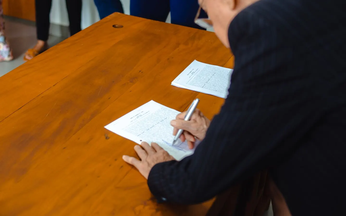 Business professional signing company documents at an office desk